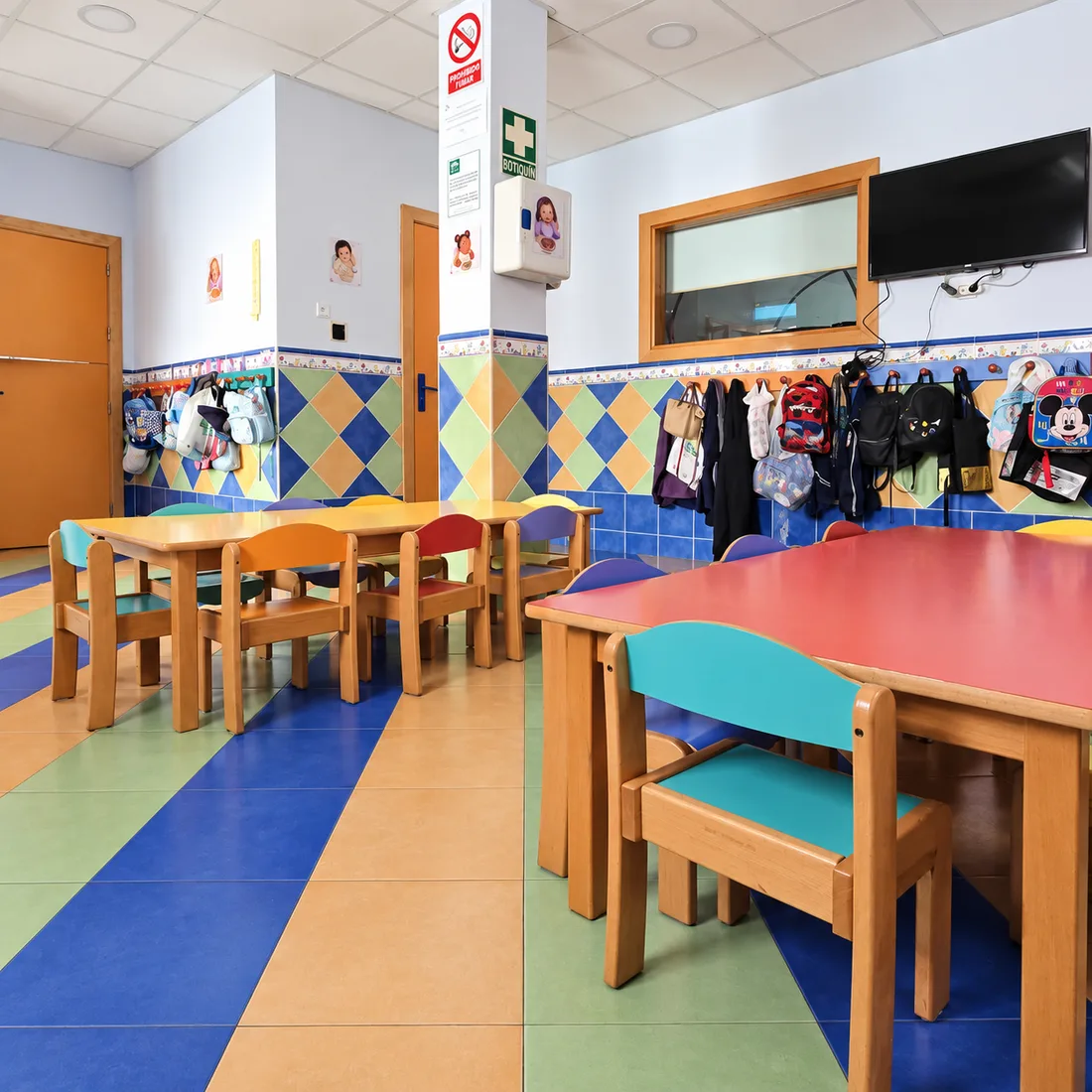 Comedor con mesas de colores y perchero para las mochilas