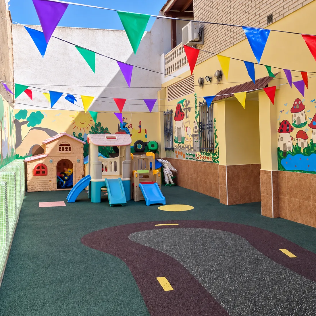 Patio exterior con toboganes, casita y suelo de caucho de colores